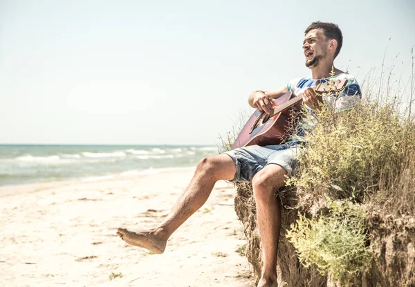 Νεαρός άνδρας με ακουστική κιθάρα στην παραλία, η έννοια του ελεύθερου χρόνου και τη δημιουργικότητα — Φωτογραφία Αρχείου