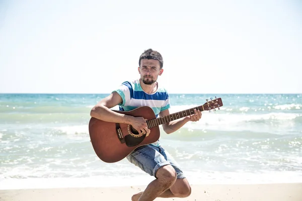 Νεαρός άνδρας με ακουστική κιθάρα στην παραλία — Φωτογραφία Αρχείου