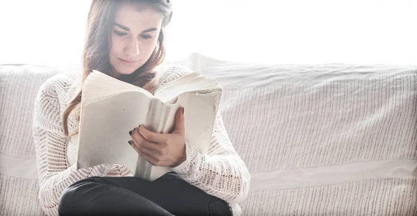 Chica leyendo libro en sofá — Foto de Stock