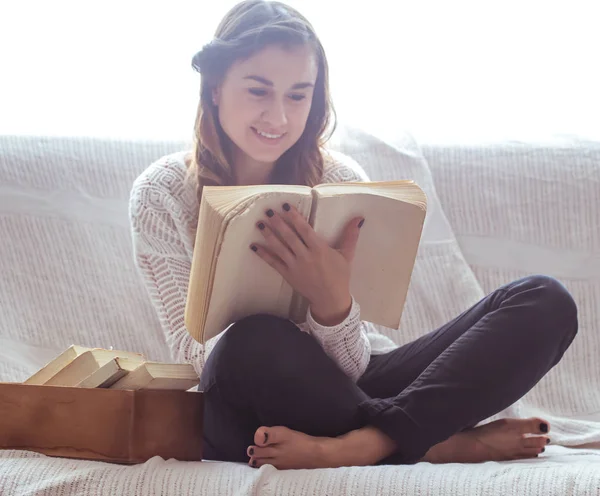 Menina leitura livro no sofá — Fotografia de Stock