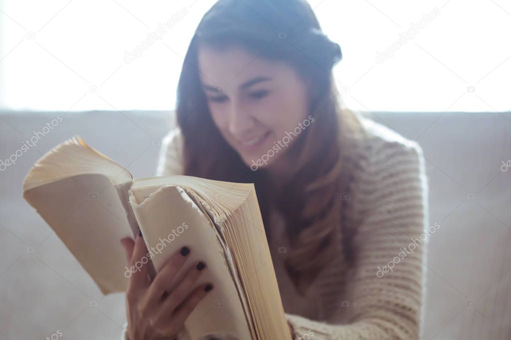 girl reading a book closeup on the sofa