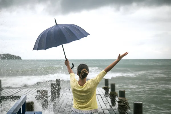 Une jeune fille sur une jetée avec un parapluie — Photo