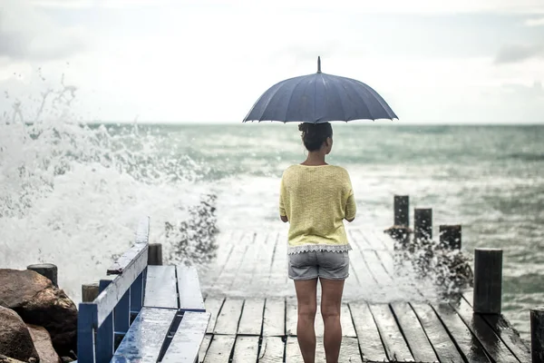 Une jeune fille sur une jetée avec un parapluie — Photo