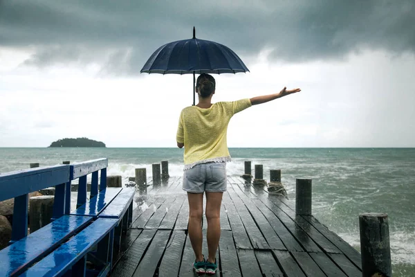 Een jong meisje op een pier met een paraplu — Stockfoto