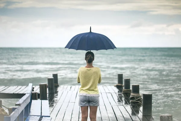 Une jeune fille sur une jetée avec un parapluie — Photo