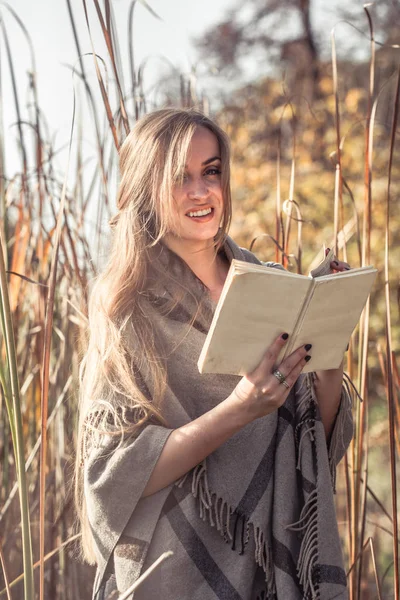 Menina bonita lendo um livro na floresta de outono — Fotografia de Stock