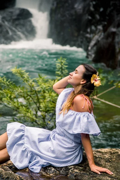 Mädchen sitzt am Wasserfall — Stockfoto