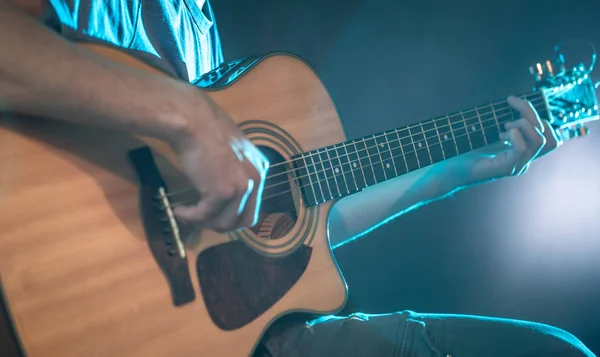 The hand of man playing acoustic guitar, close-up, flash of light, a beautiful light in the background — Stock Photo, Image