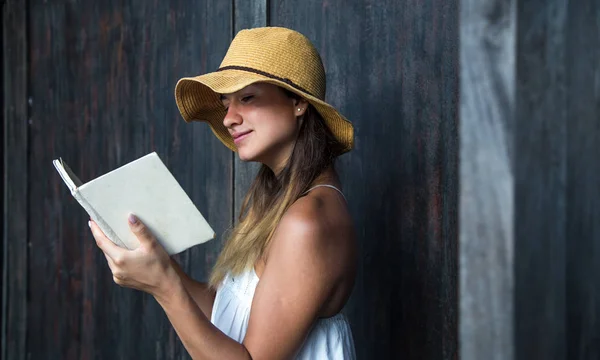 Menina lendo um livro contra uma parede na rua — Fotografia de Stock