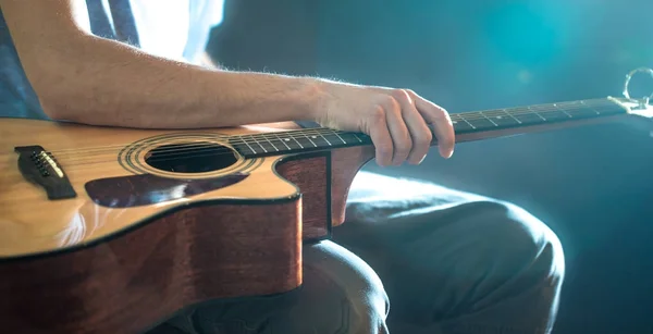 Homem sentado com uma guitarra acústica, close-up, flash de luz, um — Fotografia de Stock
