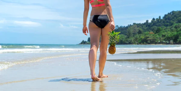 Hermosa chica con un sombrero de paja y una piña caminando en una playa exótica, buena comida y descanso — Foto de Stock