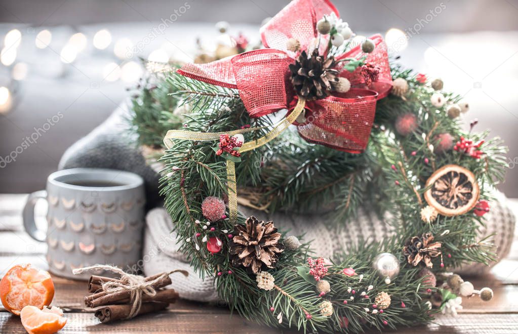 Christmas still life of trees and decorations, festive wreath on a background of knitted clothes and beautiful cups