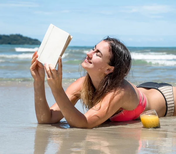 Hermosa chica acostada en la playa leyendo un libro con summ fresco — Foto de Stock