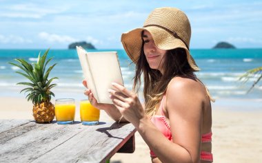 bir kız deniz kıyısında kitap okur