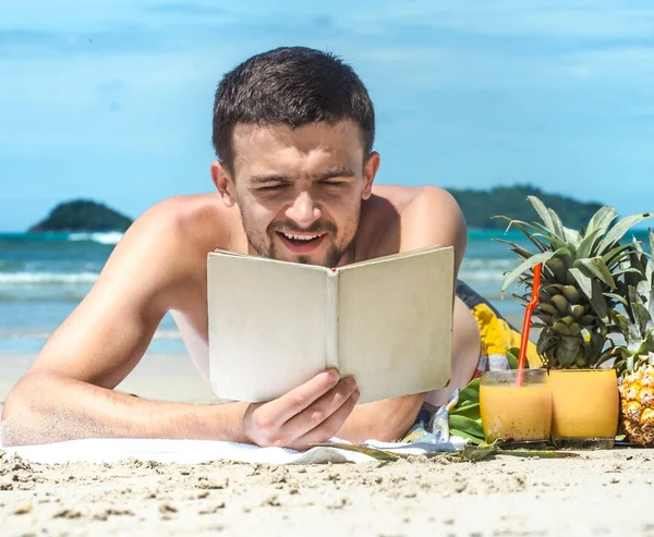 Adam sahilde yalan ve arka plan üzerine bir kitap okuma — Stok fotoğraf