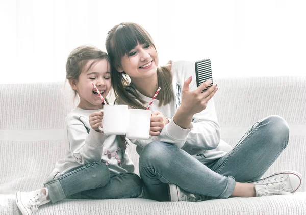 Mom and daughter drink tea on the couch