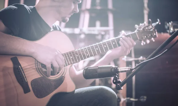 Studio mikrofonen registrerar en akustisk gitarr närbild. Vackra suddig bakgrund av färgade lanternor. — Stockfoto