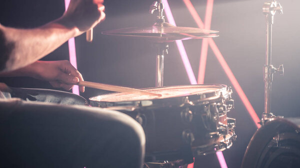 человек играет на барабанах. На фоне цветных огней
.