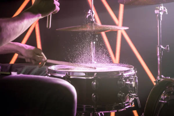 O homem toca bateria, no fundo de luzes coloridas — Fotografia de Stock