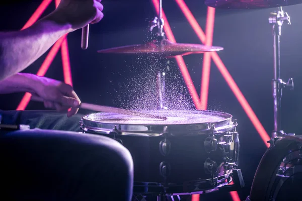 O homem toca bateria, no fundo de luzes coloridas — Fotografia de Stock