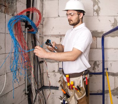 Kurulun yanında kablolarla çalışan bir elektrikçi. Kurulum ve 