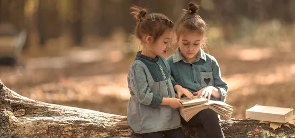 Zwei kleine Mädchen lesen Bücher im Wald. — Stockfoto