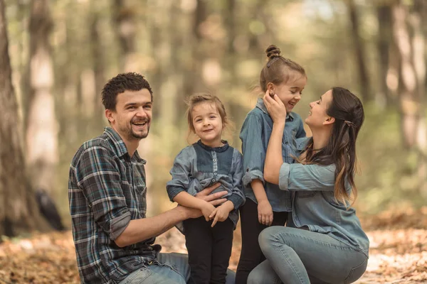 Una familia joven camina en el bosque de otoño con niños . —  Fotos de Stock