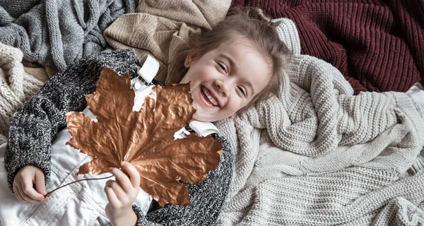 Retrato de uma menina bonita em uma camisola com uma folha em seu h — Fotografia de Stock