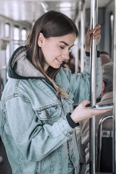 Νεαρή γυναίκα με τηλέφωνο στα μέσα μαζικής μεταφοράς. — Φωτογραφία Αρχείου