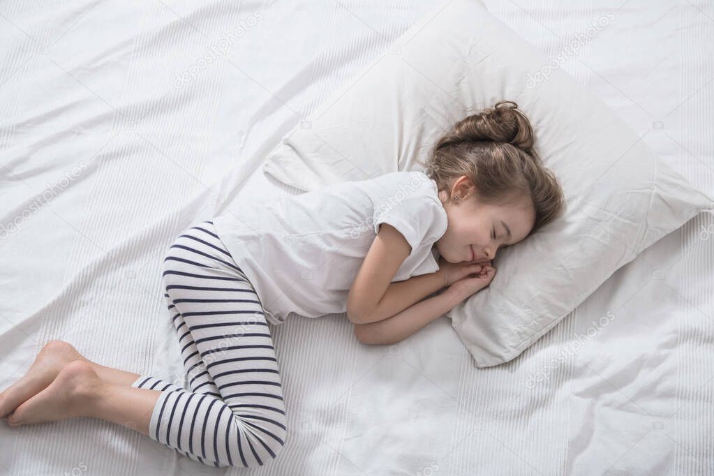 Cute little girl with long hair sleeping in bed.