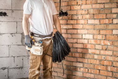 Aletleri olan bir elektrikçi, inşaat alanında çalışıyor. Tamir et.