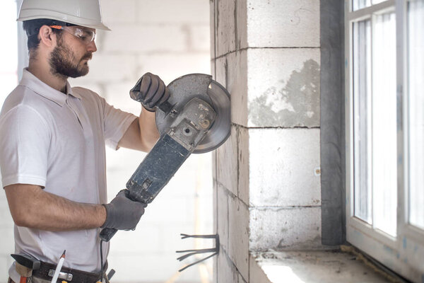 The industrial Builder works with a professional angle grinder t