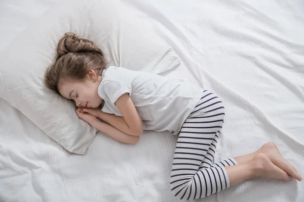 Süßes kleines Mädchen mit langen Haaren schläft im Bett. — Stockfoto