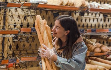 Süpermarkette genç bir kadın ve taze ekmek. .