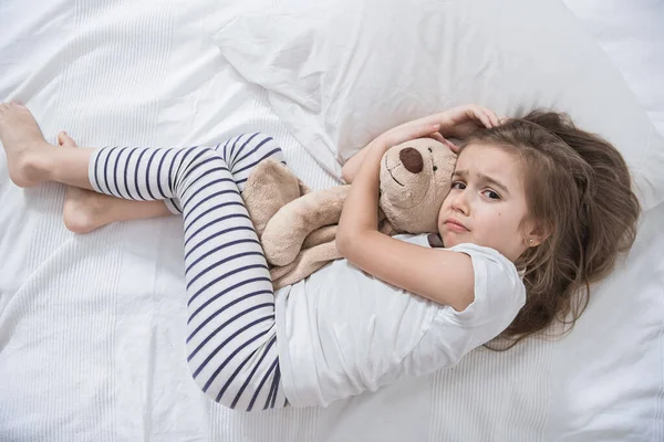 Χαριτωμένο κοριτσάκι στο κρεβάτι με μαλακό παιχνίδι. — Φωτογραφία Αρχείου