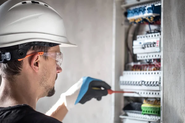 Man, een elektrotechnicus die werkt in een schakelbord met zekering — Stockfoto