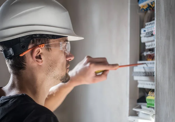 Man, een elektrotechnicus die werkt in een schakelbord met zekering — Stockfoto