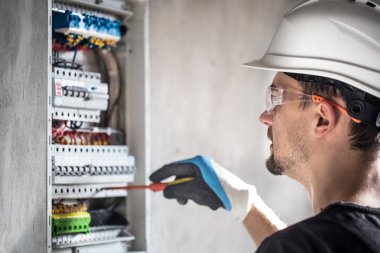 Elektrik santralinde fitili olan bir elektrik teknisyeni.