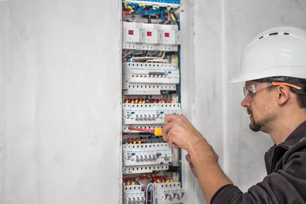 Man, an electrical technician working in a switchboard with fuse