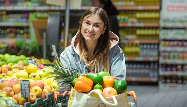A young woman buys groceries in a supermarket.