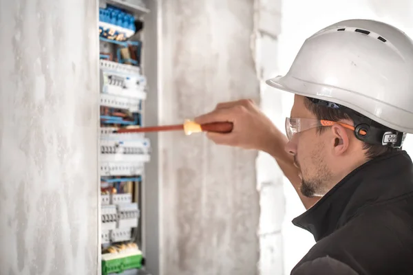 Man, een elektricien die werkt in een schakelbord met zekeringen. Installatie en aansluiting van elektrisch materiaal. — Stockfoto