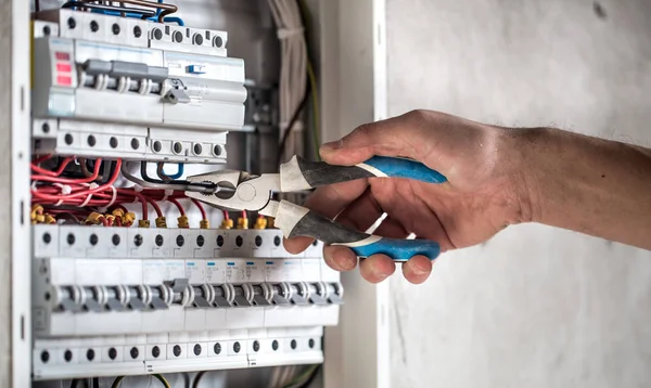 Hombre, un técnico eléctrico trabajando en una centralita con fusibles. Instalación y conexión de equipos eléctricos. De cerca. . —  Fotos de Stock