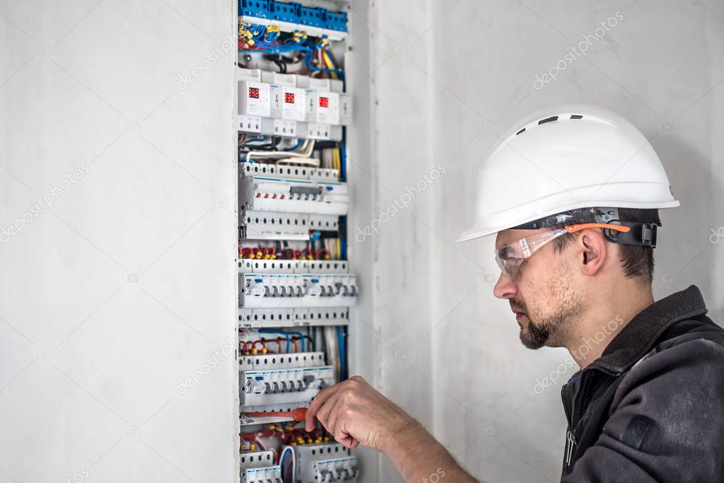 Man, an electrical technician working in a switchboard with fuses. Installation and connection of electrical equipment.