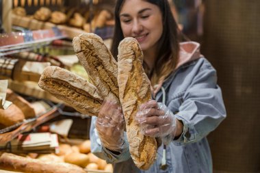 Süpermarkette genç bir kadın ve taze ekmek. .