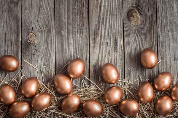 Achtergrond met gouden paaseieren op houten ondergrond. — Stockfoto