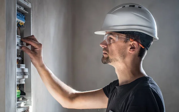 Man, an electrical technician working in a switchboard with fuse