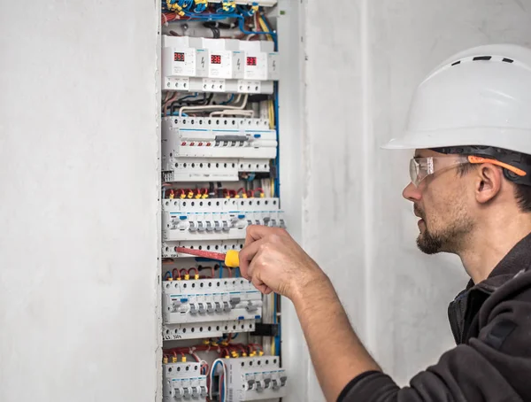 Man, een elektrotechnicus die werkt in een schakelbord met zekering — Stockfoto