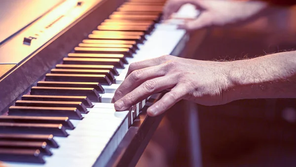 Manos masculinas en las teclas de piano primer plano de un hermoso bac colorido — Foto de Stock