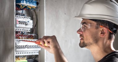 Elektrik santralinde fitili olan bir elektrik teknisyeni.