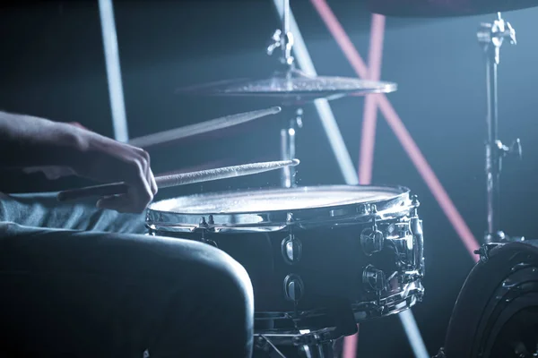 O homem toca bateria. No fundo de luzes coloridas . — Fotografia de Stock